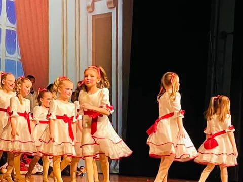 a group of girls in white dresses on a stage