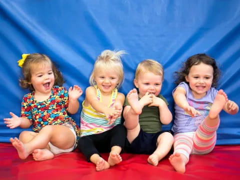 a group of children sitting on a red blanket