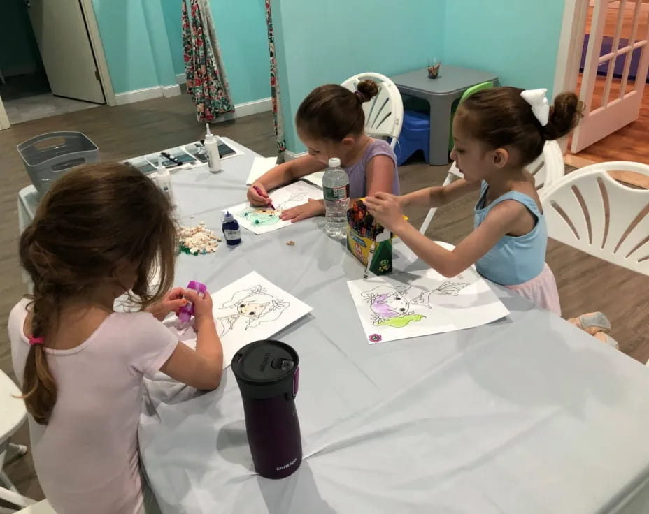 a group of girls sitting at a table painting