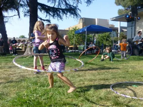 a group of girls playing with hula hoops in a yard