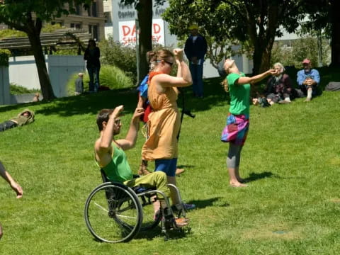 a group of people playing with a wheelchair in a park