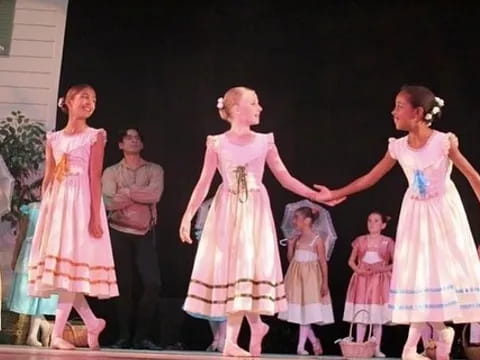 a group of children in dresses and skirts on a stage