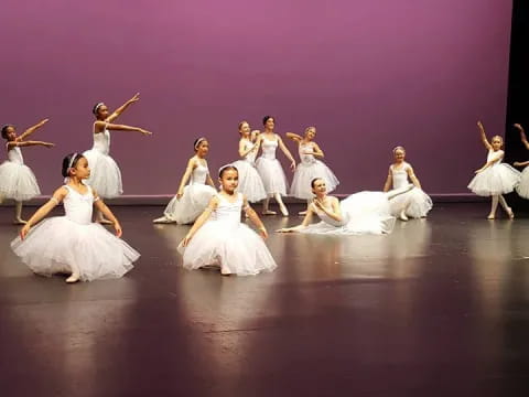 a group of women in white dresses dancing on a stage