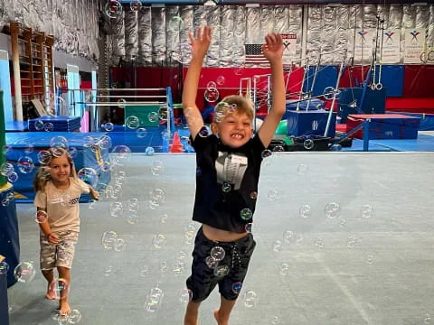 a boy standing on a trampoline with his arms up