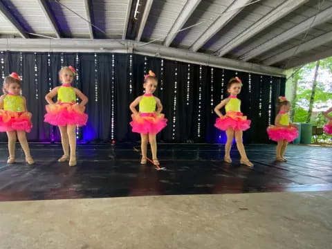 a group of girls in dresses and skirts dancing on a stage