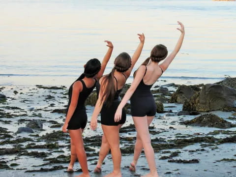 a group of women in swimsuits standing on a beach