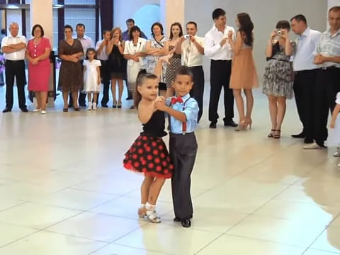 a boy and girl dancing in front of a group of people