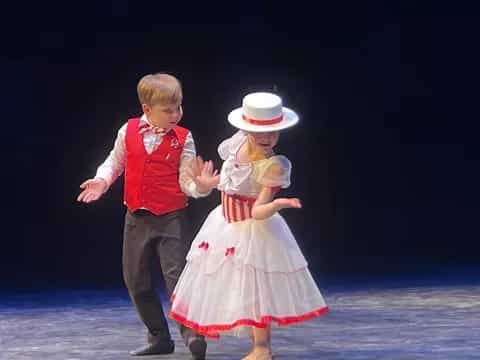 a boy and girl dancing on a stage
