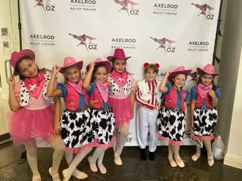 a group of girls wearing pink and white hats and standing in front of a white board with drawings