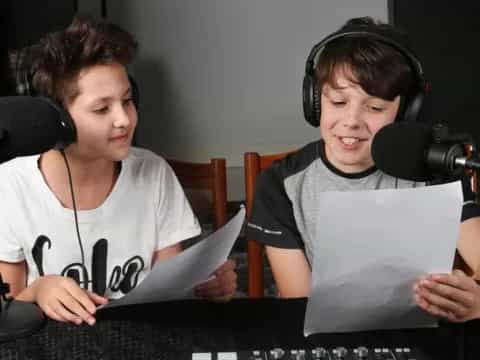 a couple of young men wearing headphones and sitting at a table