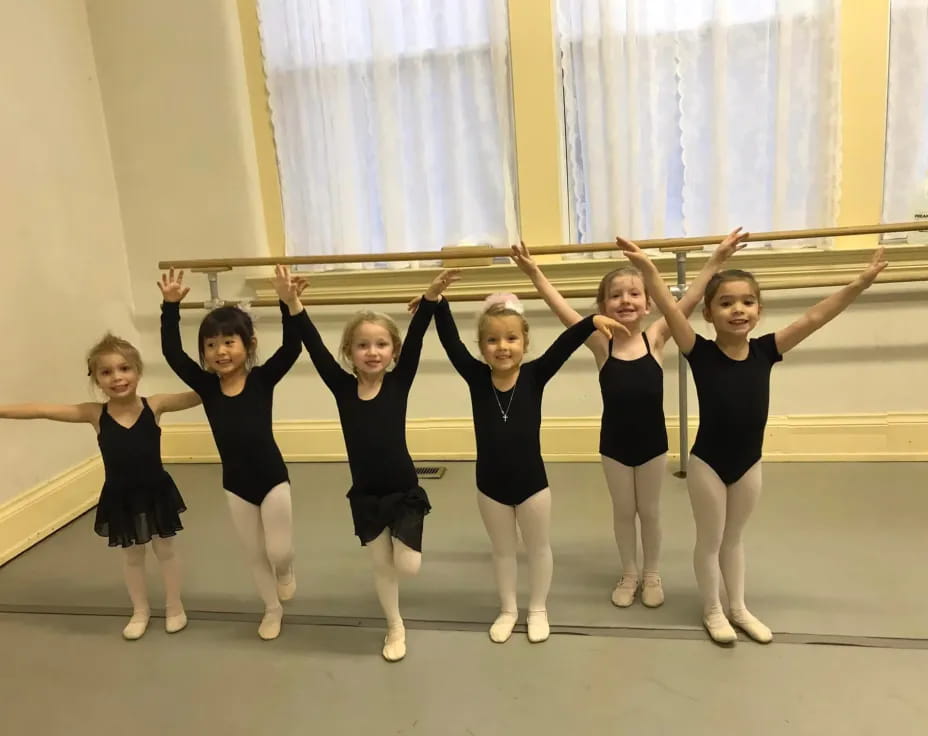 a group of girls in black ballet outfits posing for a photo