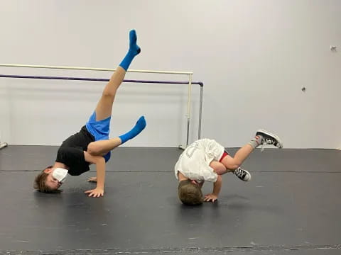 a couple of people doing handstands on a concrete floor