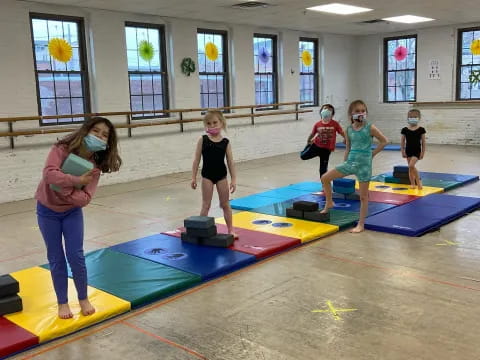 a group of kids playing on a mat in a room with windows