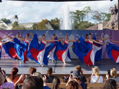 a group of people in blue and red outfits holding flags in front of a fountain
