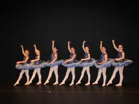 a group of women in blue ballet outfits on a stage
