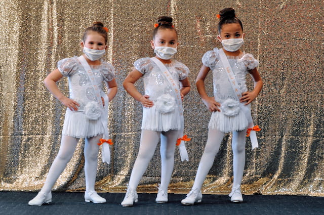 a group of girls wearing white dresses and white masks