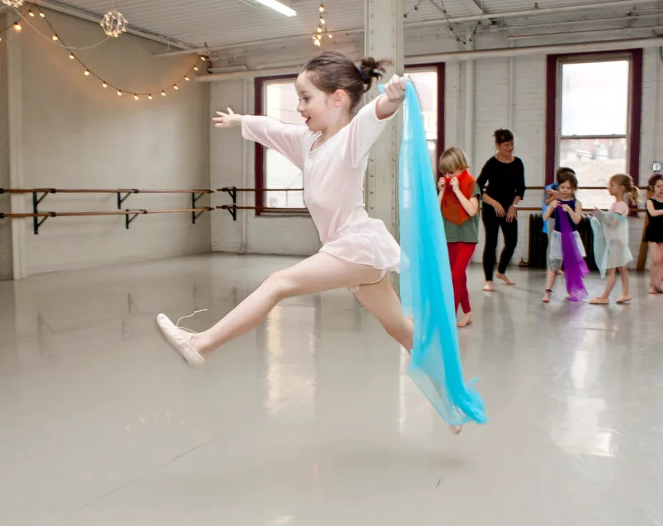 a girl dancing in a room with other children