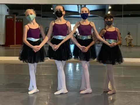 a group of women wearing masks and standing on a stage