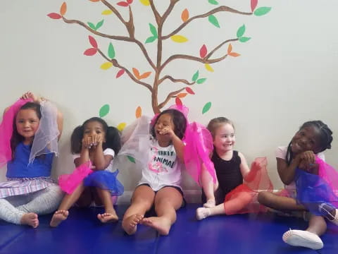 a group of children sitting on a mat posing for the camera