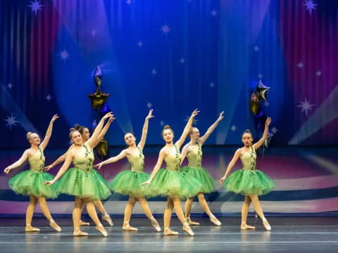 a group of girls in green dresses dancing on a stage