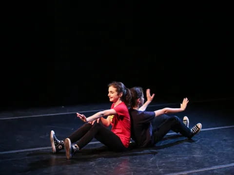 a man and woman sitting on the ground with their arms up