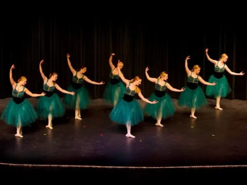 a group of women in green dresses dancing on a stage