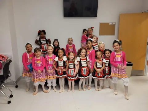 a group of girls in pink and white dresses posing for a photo