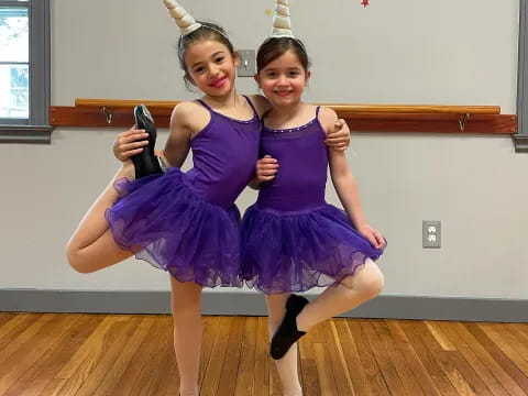 two girls wearing purple dresses and holding guns