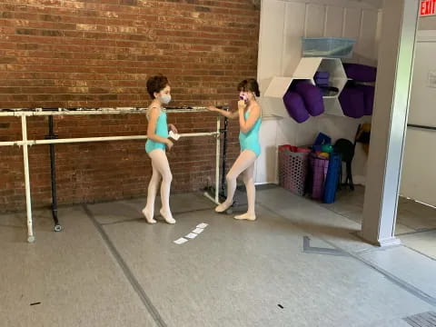 a couple of women in swimsuits in a room with a brick wall and a wood railing