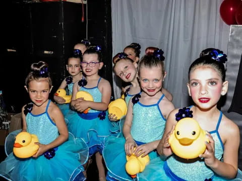 a group of girls in blue dresses holding stuffed animals