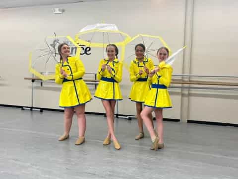 a group of women in yellow dresses holding umbrellas