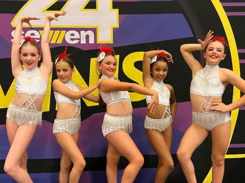 a group of women in white and black outfits on a stage