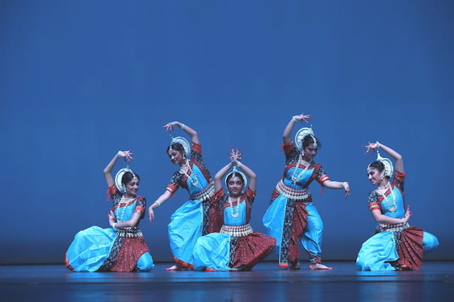 a group of women in colorful dresses dancing on a stage