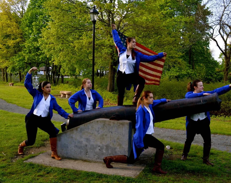a group of women jumping on a statue in a park