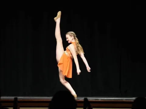 a person in an orange dress dancing on a stage