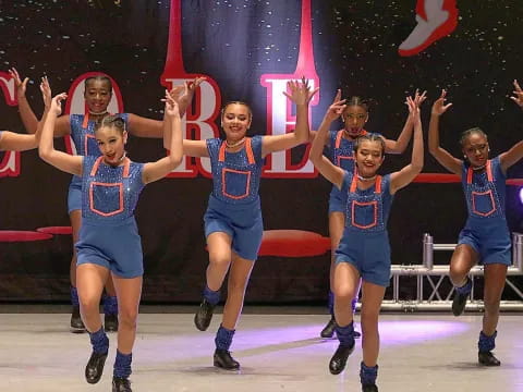 a group of cheerleaders in blue uniforms jumping in the air