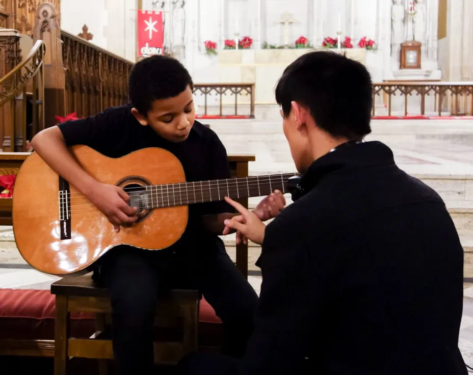 a man playing a guitar next to another man