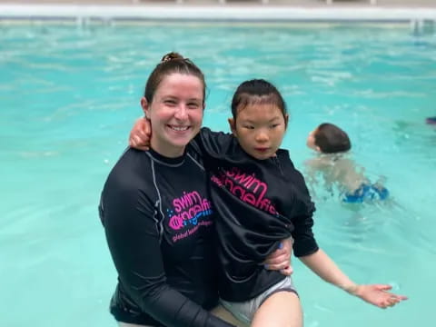 a woman holding a baby in a pool