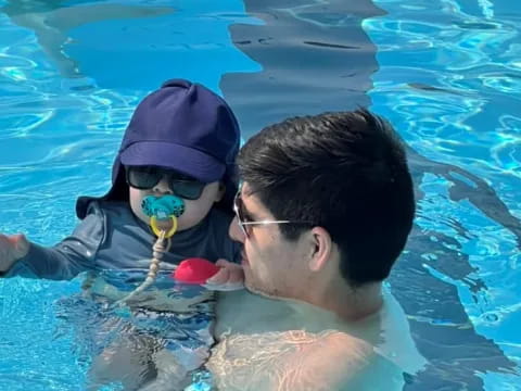 a man and a woman in a pool with a toy
