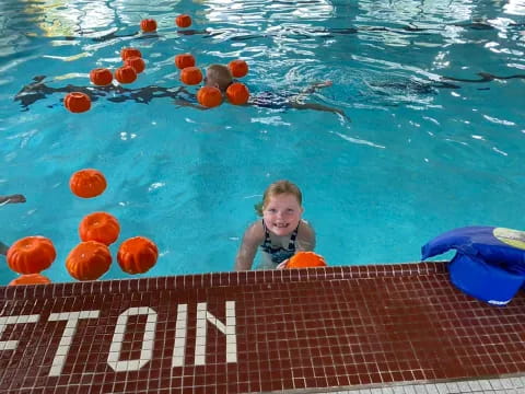 a boy in a pool with orange balls