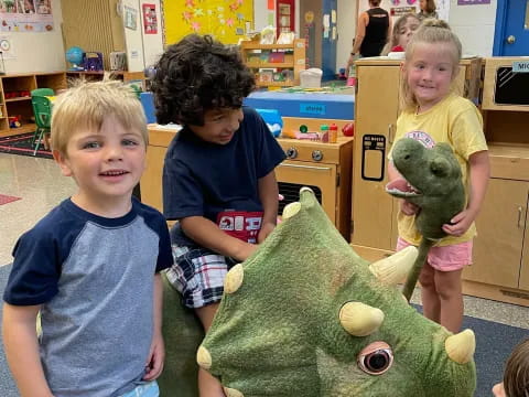 a group of children posing with a stuffed animal