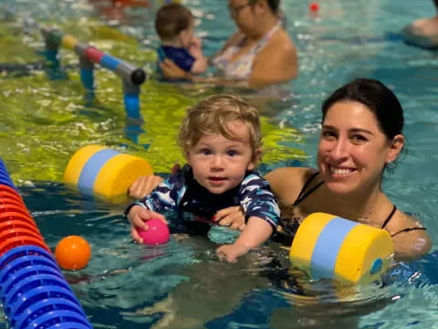 a person and a child in a pool with balls