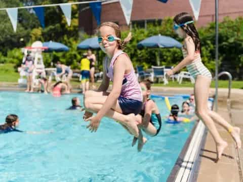 a couple of girls jumping into a pool