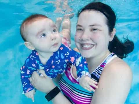 a person holding a baby in a pool