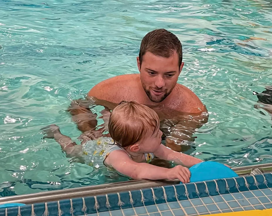 a man holding a baby in a pool
