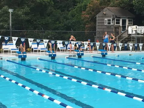 a group of people standing around a swimming pool