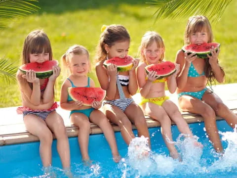 a group of girls in swimsuits eating watermelon