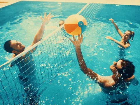 a group of people playing in a pool with a ball