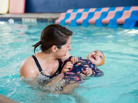 a person holding a baby in a pool