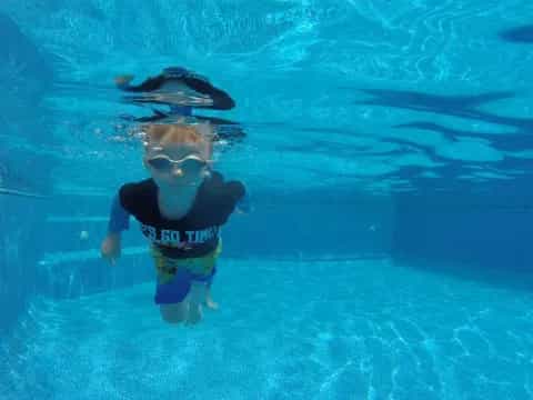 a boy in a pool with a fish on his head